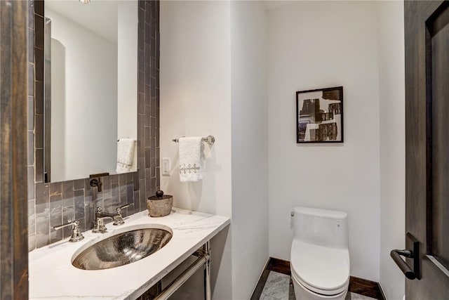 bathroom with vanity, toilet, and tasteful backsplash