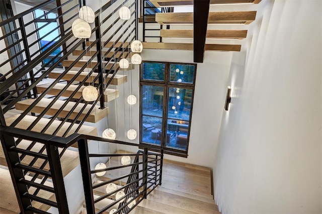 staircase featuring wood-type flooring and beam ceiling