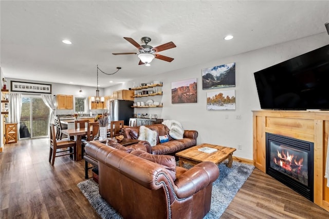 living room with wood-type flooring and ceiling fan with notable chandelier