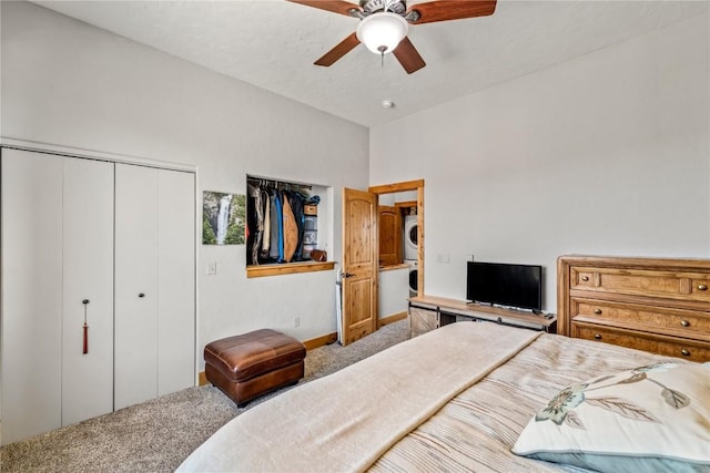 bedroom with carpet flooring, ceiling fan, and stacked washing maching and dryer