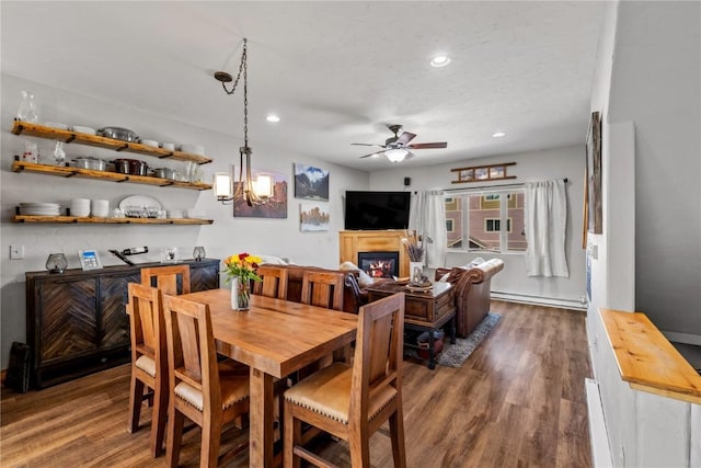 dining space with ceiling fan with notable chandelier and dark wood-type flooring