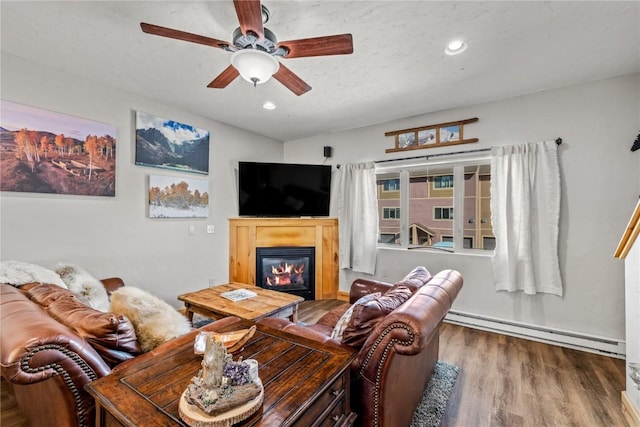 living room with wood-type flooring, baseboard heating, and ceiling fan