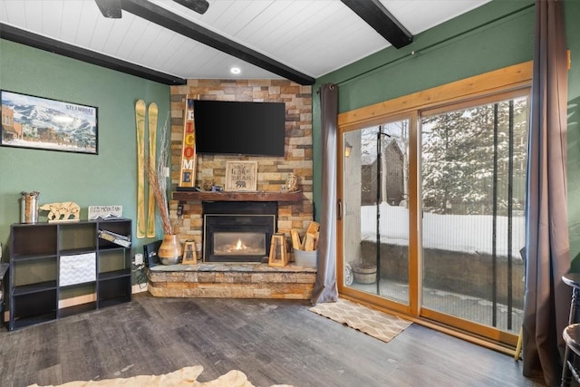 living room featuring lofted ceiling with beams, ceiling fan, hardwood / wood-style flooring, and a stone fireplace