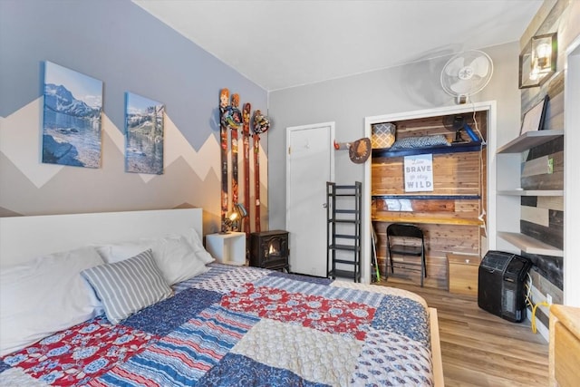 bedroom with a wood stove and wood-type flooring