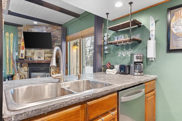 kitchen featuring dishwasher, sink, wood ceiling, vaulted ceiling with beams, and a stone fireplace