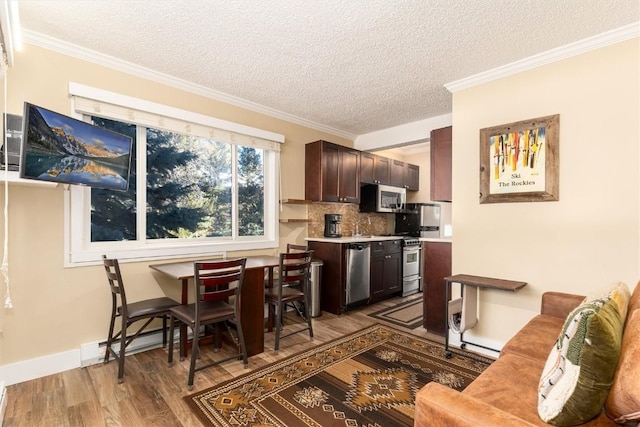 kitchen with appliances with stainless steel finishes, backsplash, dark brown cabinets, a textured ceiling, and wood-type flooring