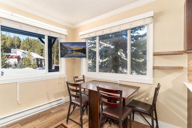 dining area with a textured ceiling, hardwood / wood-style flooring, crown molding, and a baseboard heating unit