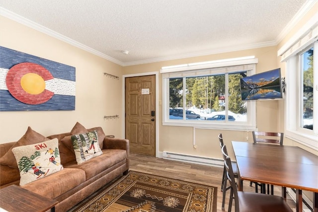 living room featuring hardwood / wood-style flooring, ornamental molding, a textured ceiling, and a baseboard heating unit