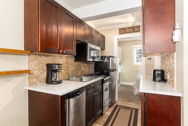 kitchen with tasteful backsplash, a textured ceiling, stainless steel appliances, crown molding, and sink