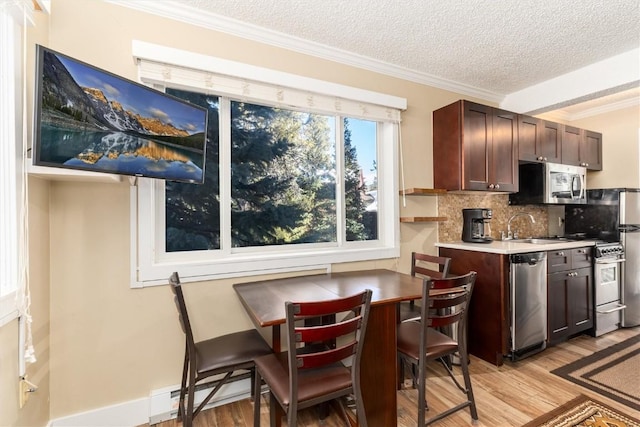 kitchen featuring decorative backsplash, light wood-type flooring, dark brown cabinets, a textured ceiling, and stainless steel appliances