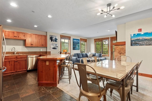 kitchen featuring recessed lighting, baseboards, stainless steel dishwasher, a chandelier, and a kitchen breakfast bar