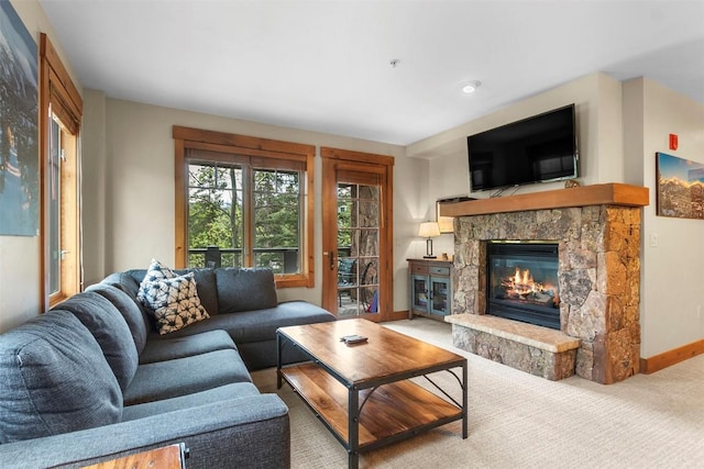 carpeted living room featuring a stone fireplace and baseboards