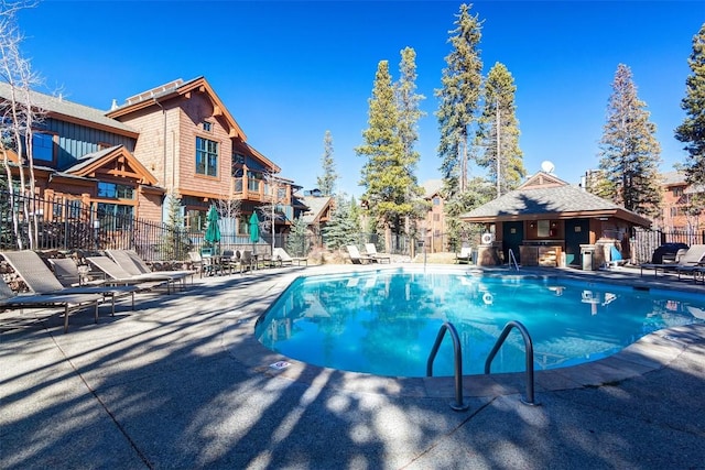 pool with a patio and fence