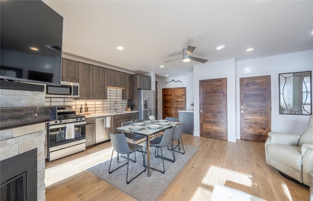 kitchen featuring sink, dark brown cabinets, appliances with stainless steel finishes, light hardwood / wood-style floors, and backsplash