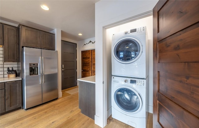 washroom featuring light hardwood / wood-style floors and stacked washing maching and dryer