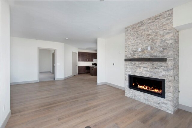 unfurnished living room featuring a stone fireplace and light hardwood / wood-style flooring