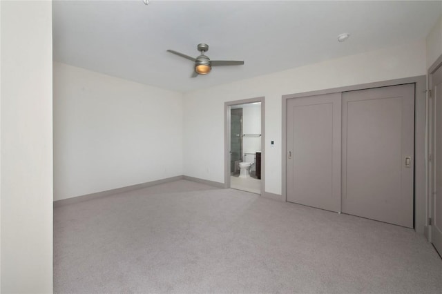 unfurnished bedroom with ceiling fan, a closet, light colored carpet, and ensuite bathroom