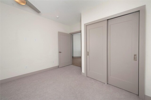 unfurnished bedroom featuring light carpet, a closet, and ceiling fan