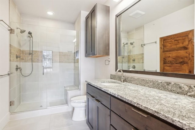 bathroom with tile patterned flooring, vanity, a shower with shower door, and toilet