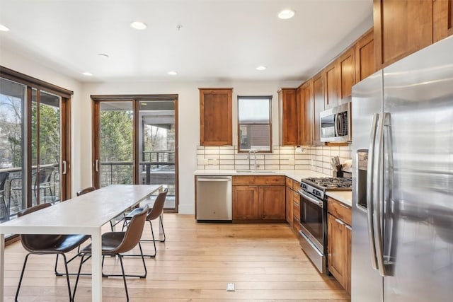 kitchen featuring backsplash, sink, light hardwood / wood-style flooring, and appliances with stainless steel finishes