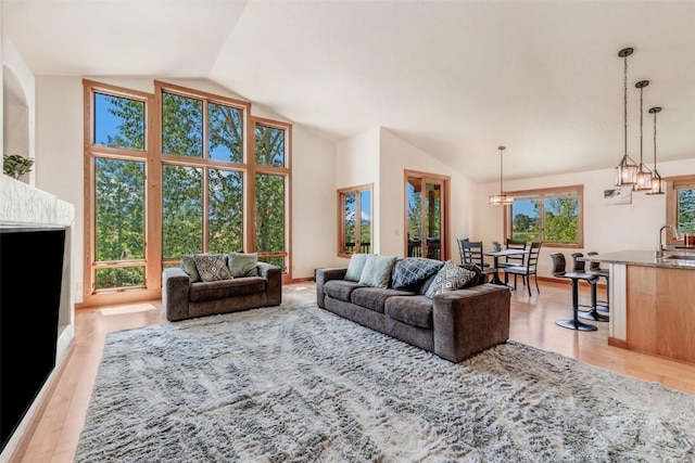 living room with light hardwood / wood-style flooring, vaulted ceiling, and sink