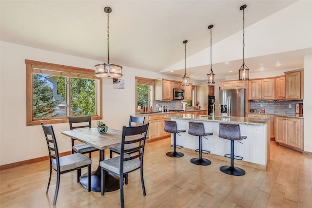 dining room with sink, lofted ceiling, and light wood-type flooring