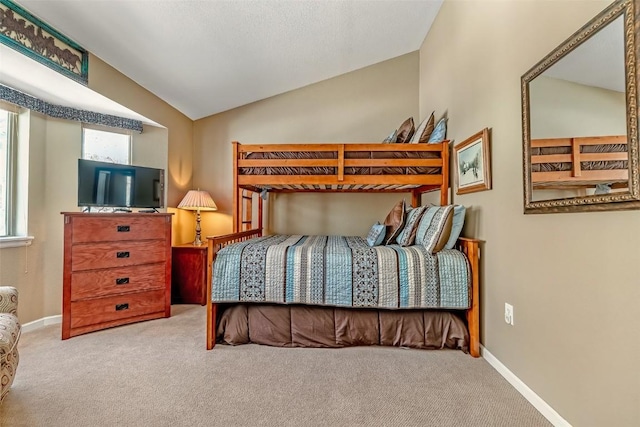 carpeted bedroom with lofted ceiling and baseboards