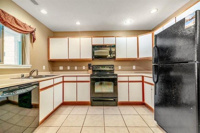 kitchen with light tile patterned floors, black appliances, a sink, and light countertops