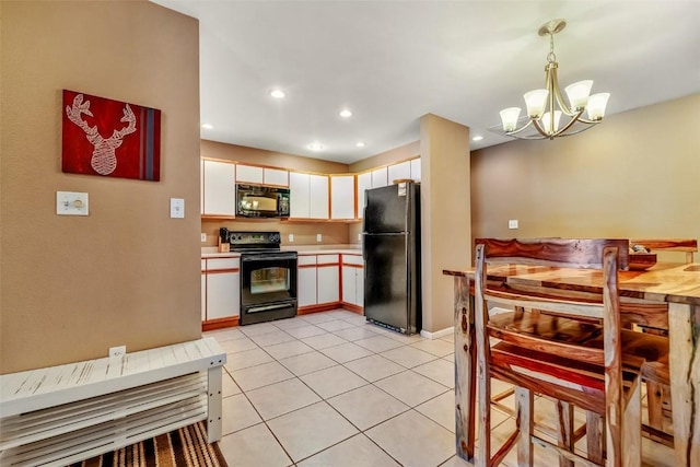 kitchen with light tile patterned floors, white cabinets, light countertops, black appliances, and a chandelier