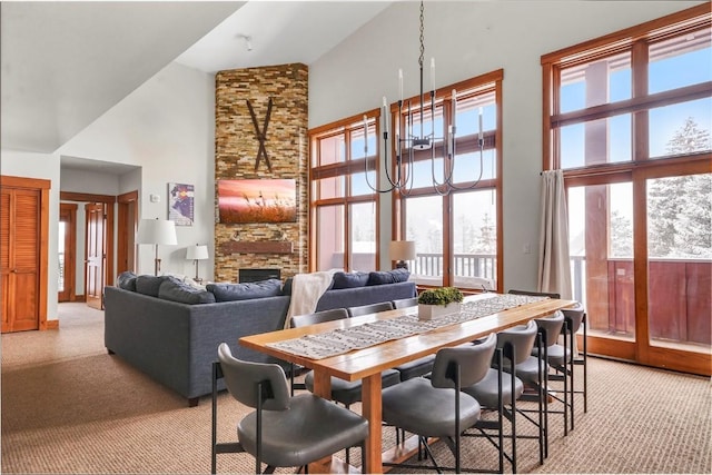 dining area with a towering ceiling, light carpet, a fireplace, and a notable chandelier