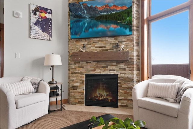 carpeted living area featuring a stone fireplace