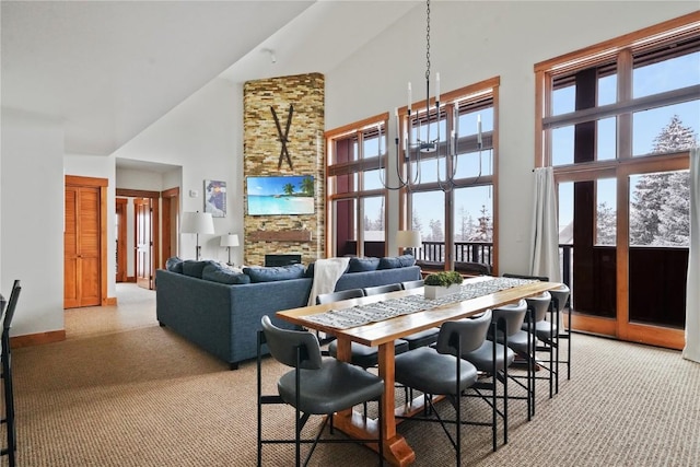 dining room with light carpet, high vaulted ceiling, a wealth of natural light, and a stone fireplace