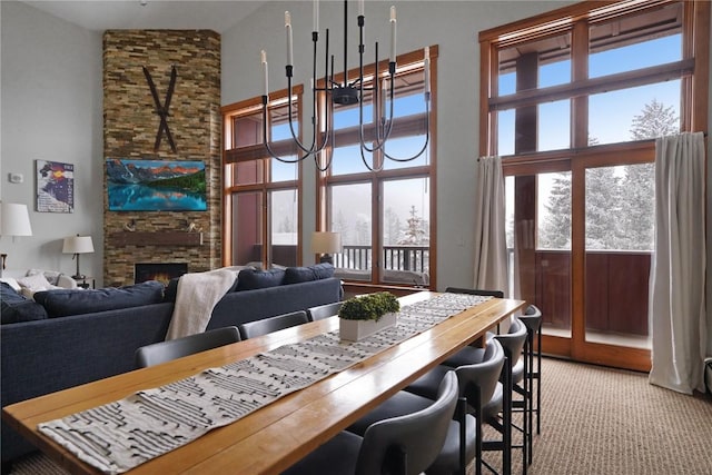 dining area featuring a high ceiling, a fireplace, and light colored carpet