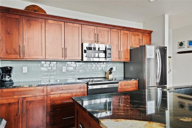 kitchen featuring stainless steel appliances, brown cabinets, dark stone countertops, and tasteful backsplash