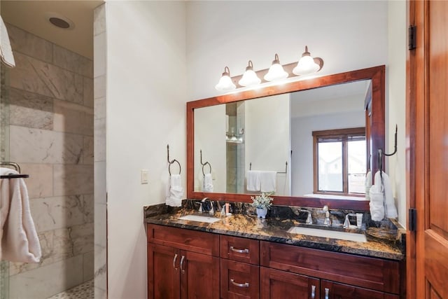 bathroom featuring double vanity, tiled shower, and a sink