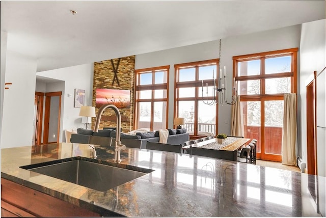 kitchen with plenty of natural light, dark stone counters, a sink, and open floor plan