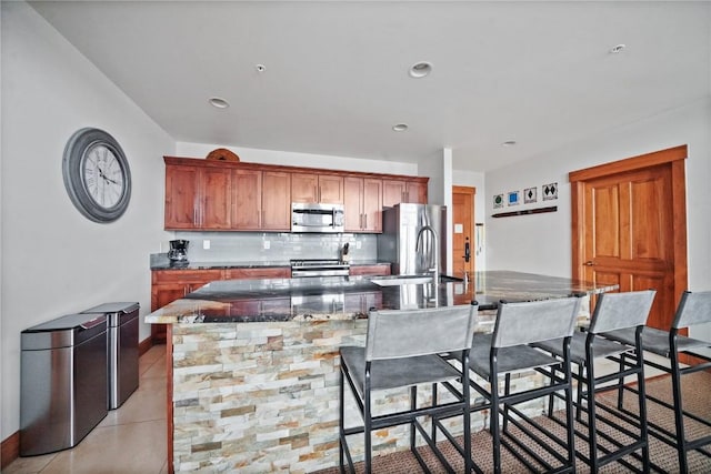 kitchen featuring tasteful backsplash, a spacious island, a kitchen breakfast bar, stainless steel appliances, and a sink