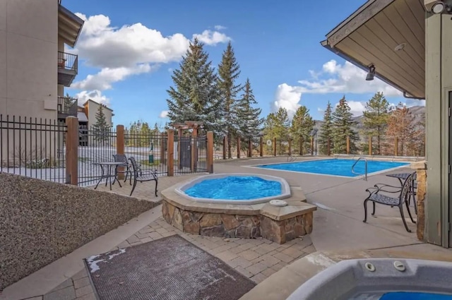 pool featuring a patio area, a community hot tub, and fence