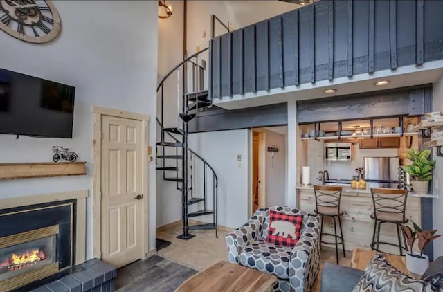 living room with stairs, a glass covered fireplace, wood finished floors, and a towering ceiling