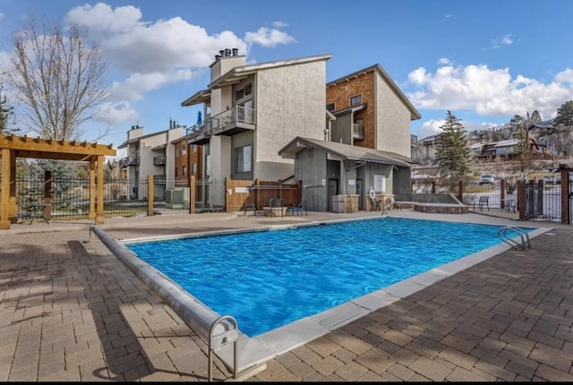 community pool featuring a patio, fence, and a residential view