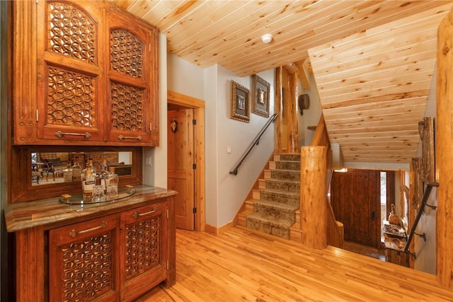 bar with light wood-type flooring, stone counters, and wooden ceiling