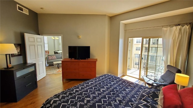 bedroom featuring a chandelier, access to outside, visible vents, and wood finished floors