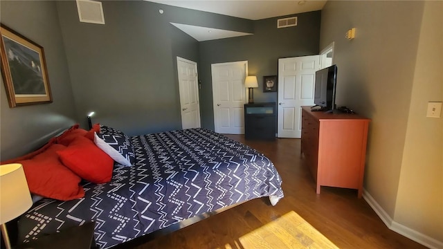 bedroom featuring baseboards, visible vents, and dark wood finished floors