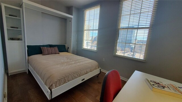 bedroom with multiple windows, dark wood finished floors, and baseboards