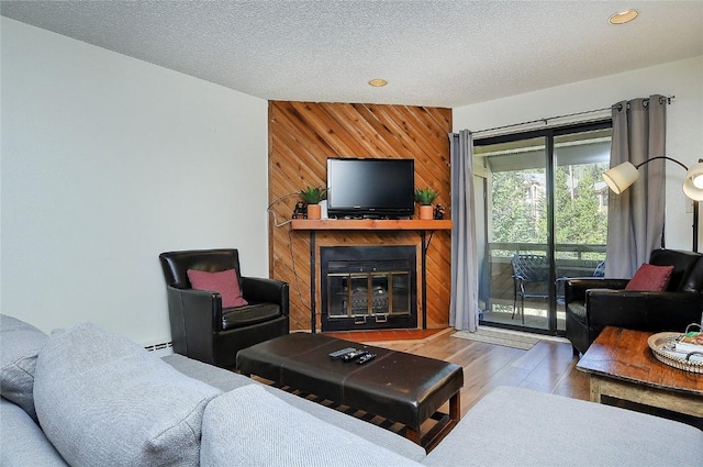 living room featuring hardwood / wood-style floors, a large fireplace, a textured ceiling, and wooden walls