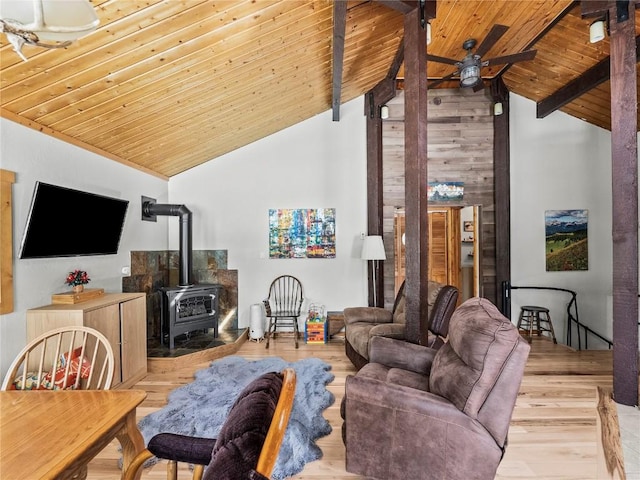 living room with a wood stove, ceiling fan, beam ceiling, wooden ceiling, and light wood-type flooring