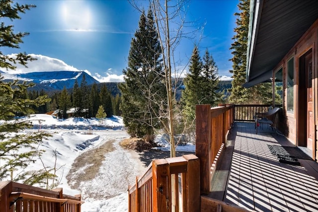 snow covered deck with a mountain view