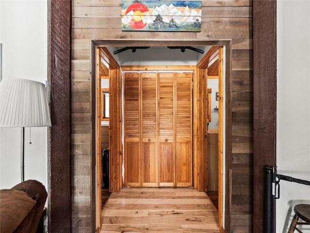 hallway with wood walls and light hardwood / wood-style flooring