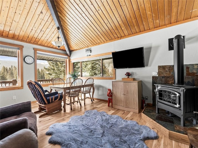 living room featuring wood ceiling, light wood-type flooring, vaulted ceiling, and a wood stove