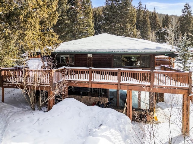 snow covered back of property with a deck